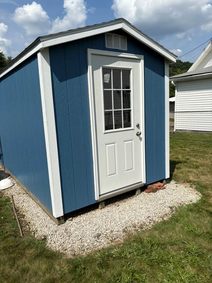 Blue storage shed on gravel foundation